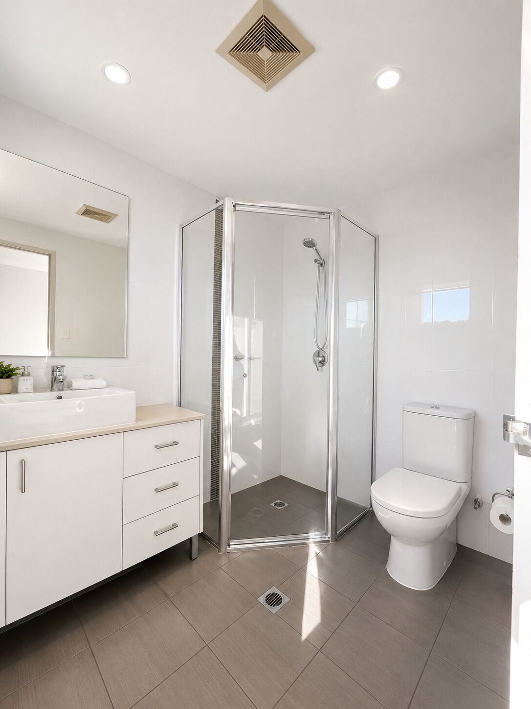 A modern bathroom with a glass-enclosed shower, a white toilet, and a vanity with drawers.