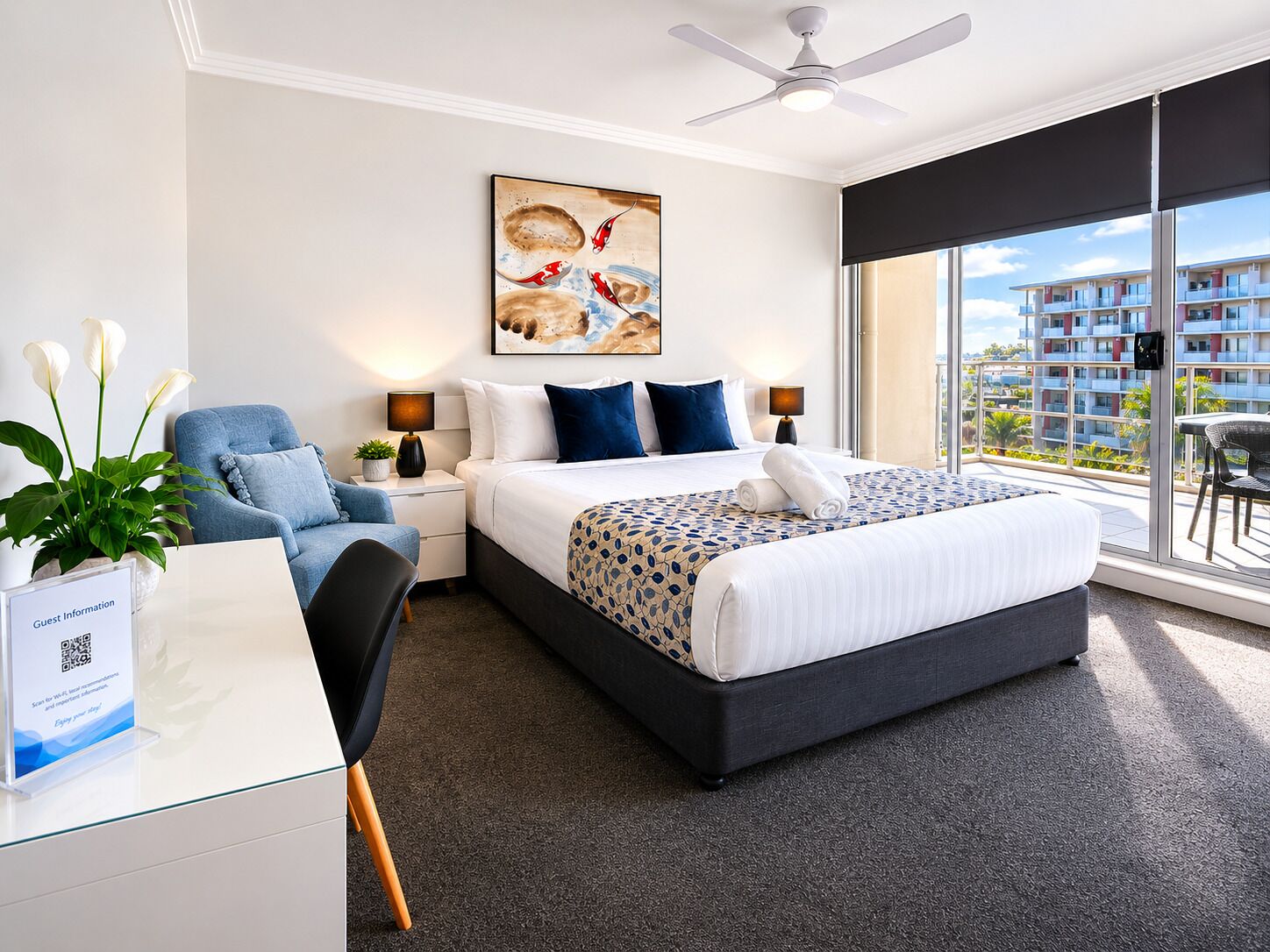 A modern hotel room with a large bed, a desk with a computer, a chair, a plant, and a view of the city.