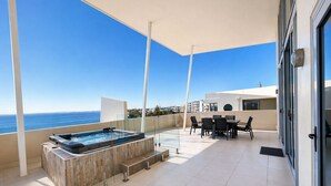 A rooftop terrace with a hot tub, outdoor seating, and a view of the sea. - Redvue Apartments (Redcliffe)