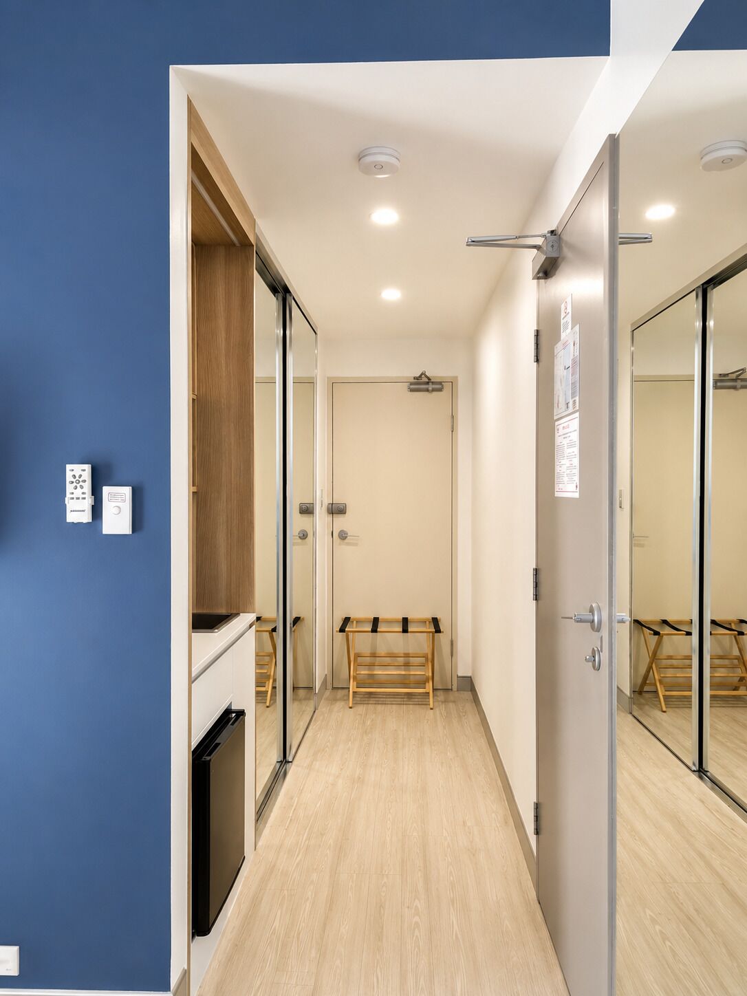 A hallway with a bench, a wooden cabinet, and a door with a mirror.