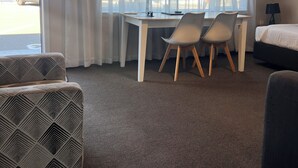 Una habitación de hotel con escritorio, dos sillas, una cama y un sillón estampado.