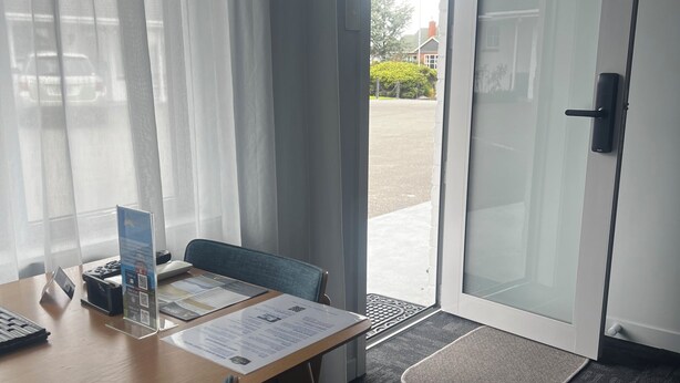 Habitación de hotel con un escritorio de madera, una silla, un vidrio y vistas al exterior.