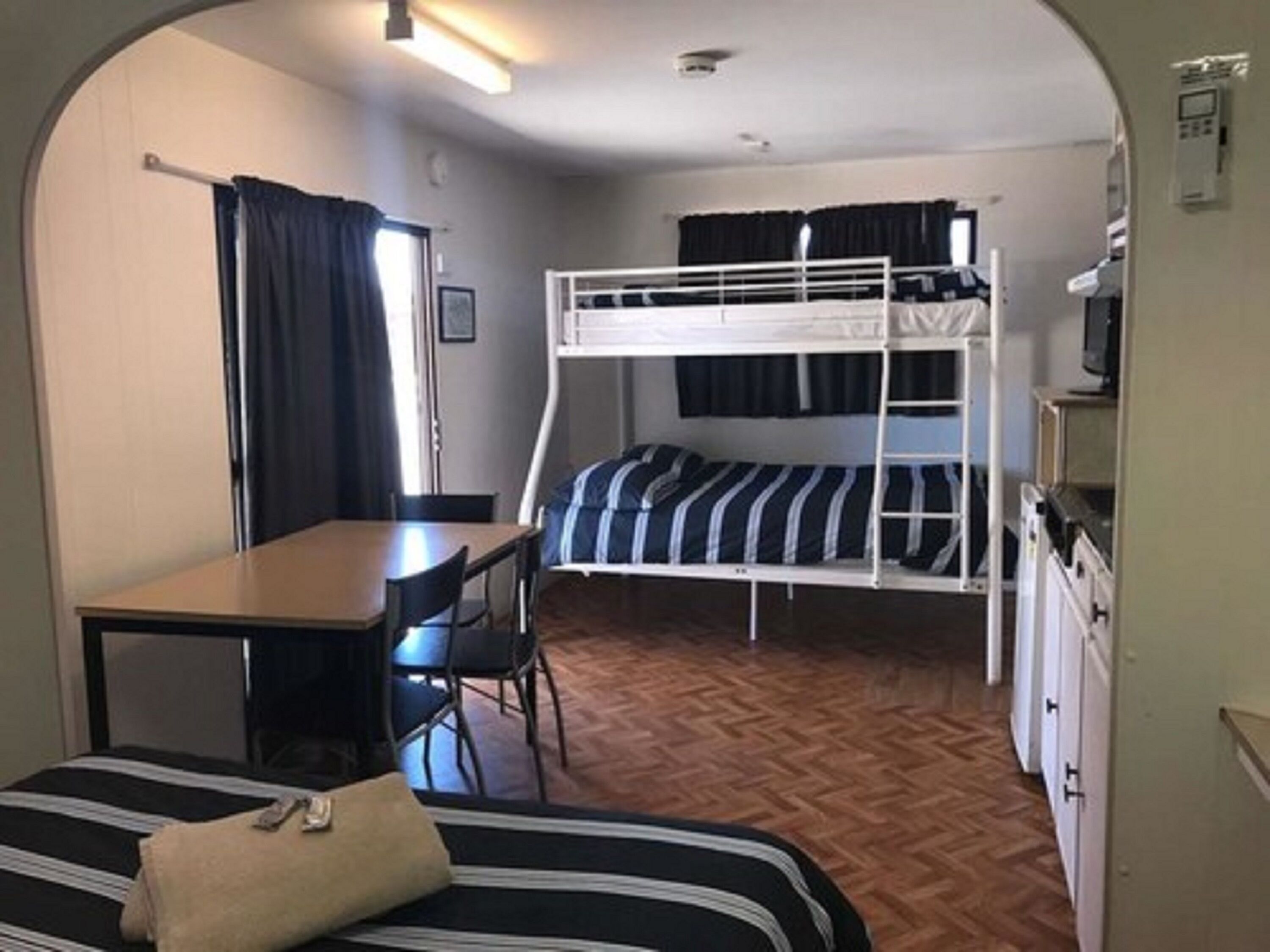 A compact room with bunk beds, a small table, and a chair.