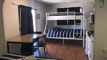 A compact room with bunk beds, a small table, and a chair.