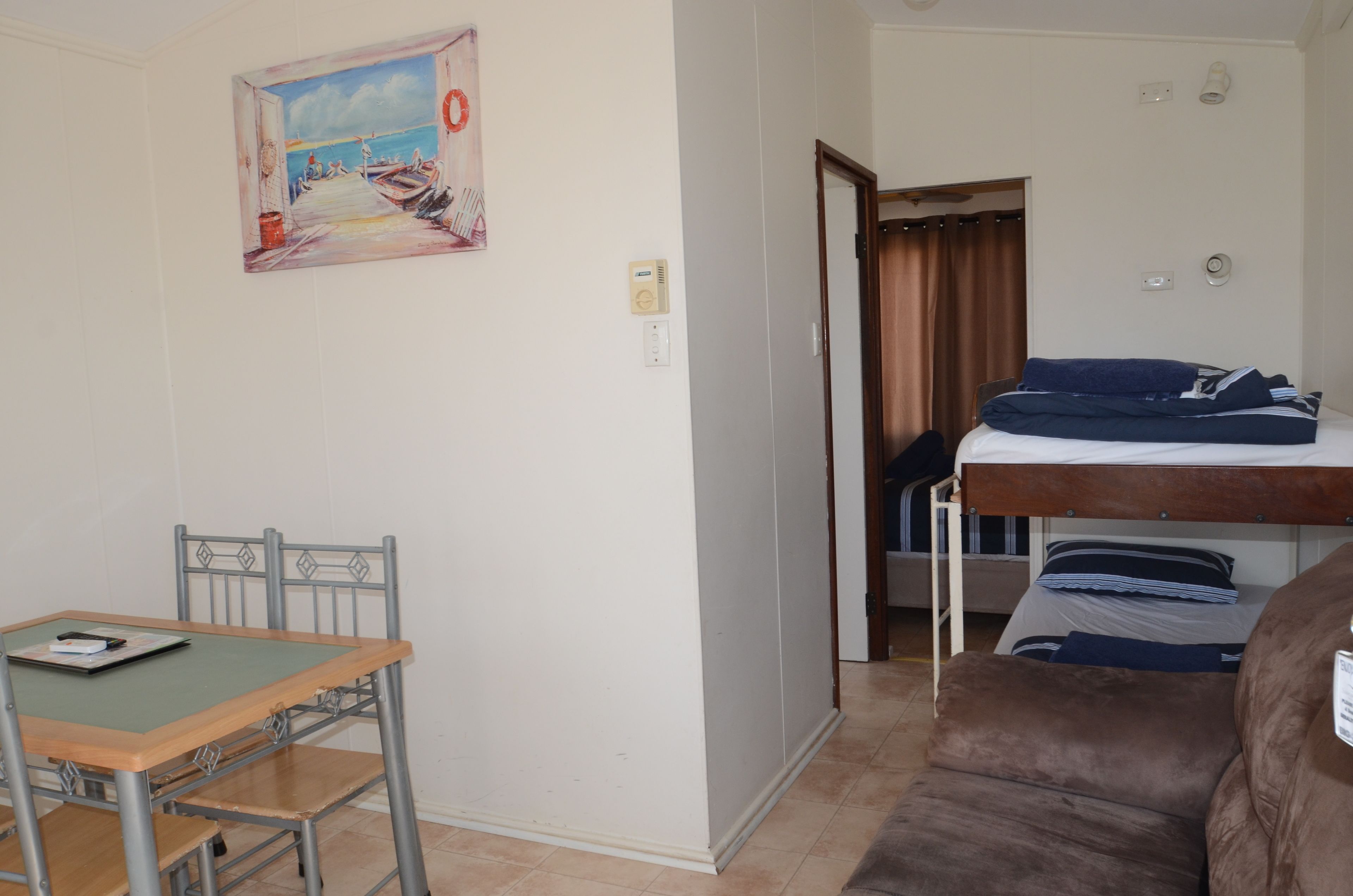 A room with a bunk bed, a desk with a chair, and a painting on the wall.