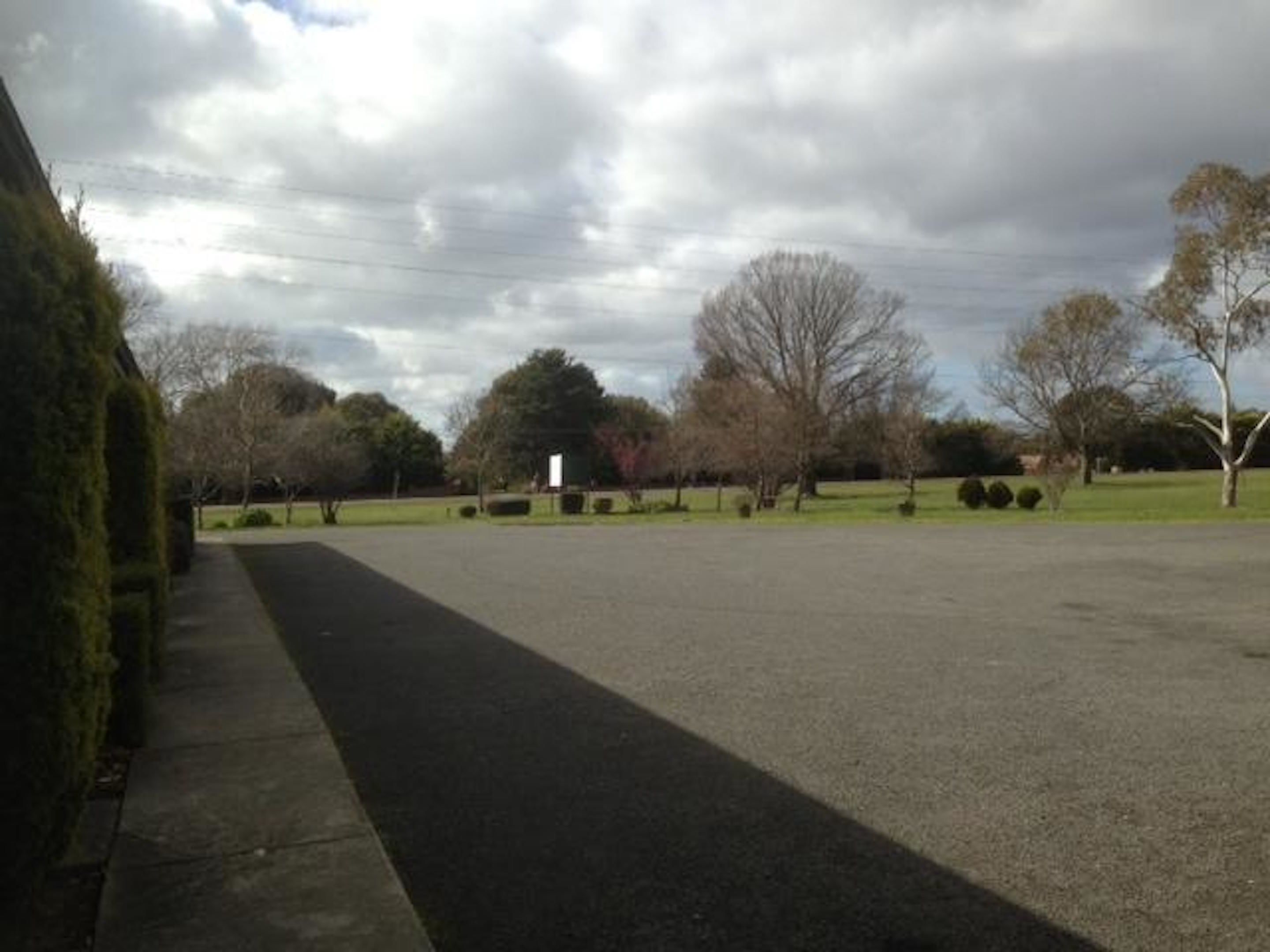 A parking lot with a paved walkway and trees.