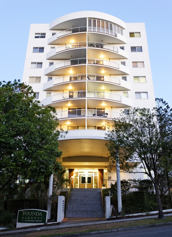 A multi-story hotel with a central entrance, balconies on each floor, and a sign indicating the name and address. - Founda Gardens Apartments (Auchenflower)