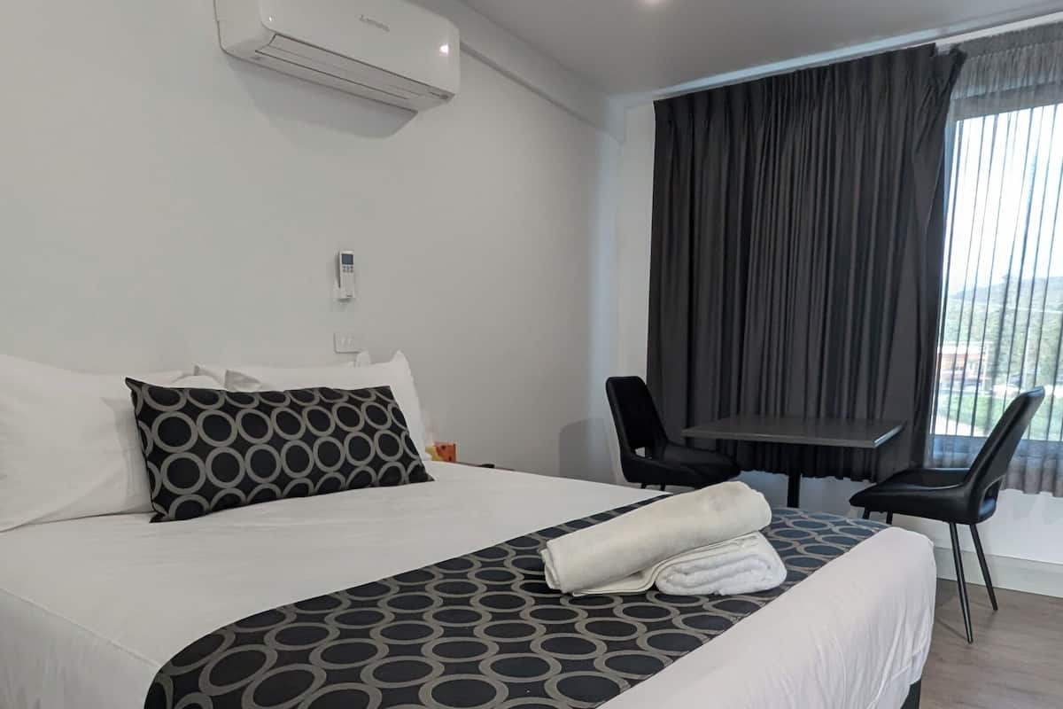 A modern hotel room with a large bed, a desk, and a chair.