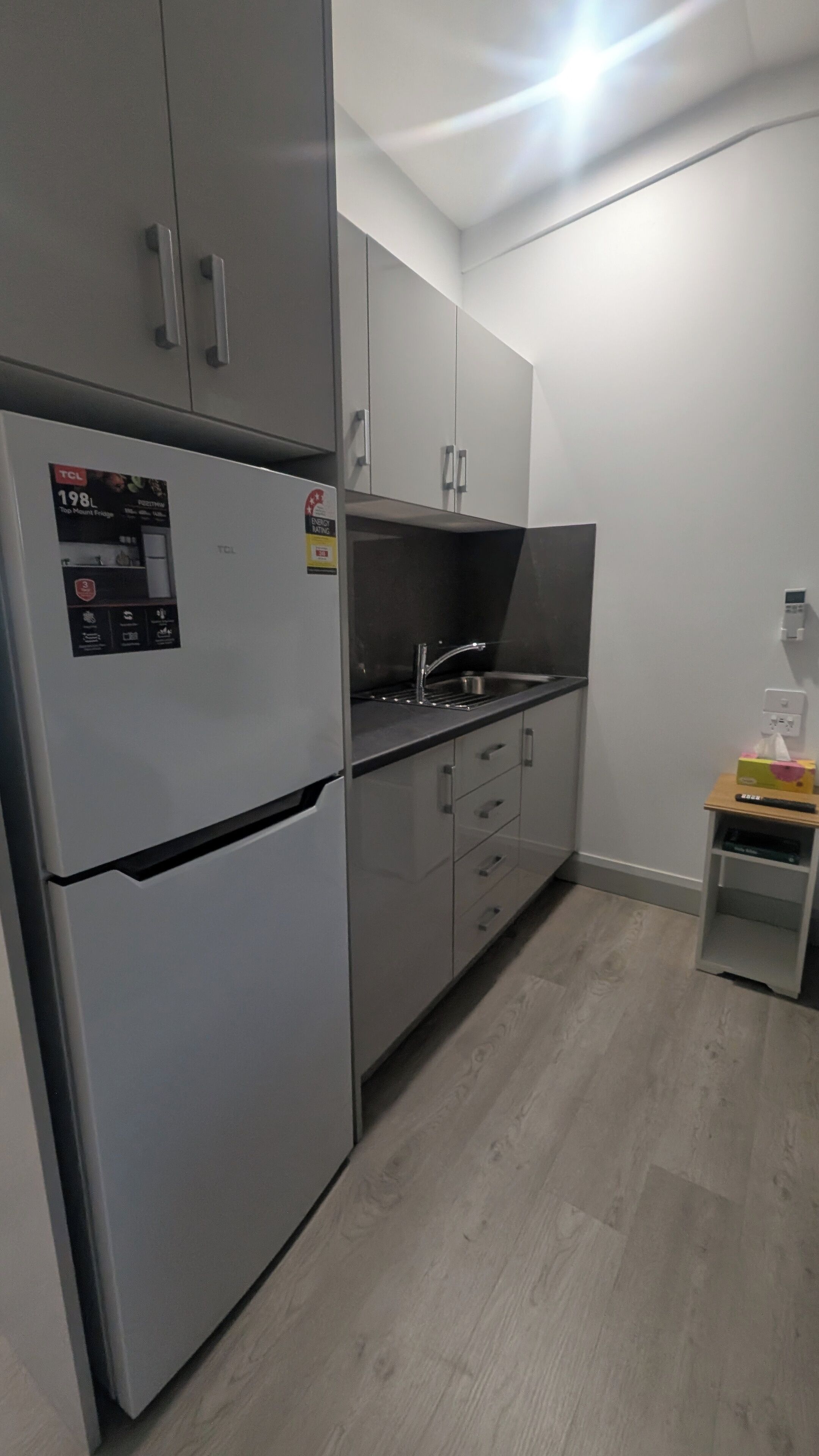 Een kleine keuken met een koelkast, gootsteen en kastjes.
