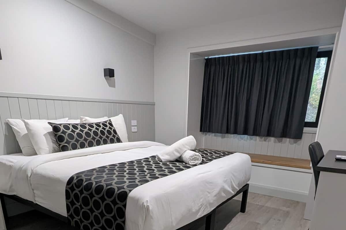 A modern bedroom with a bed, bedside tables, and a window with curtains.