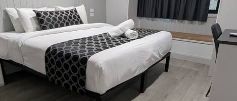 A modern bedroom with a bed, bedside tables, and a window with curtains.