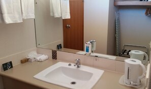 A hotel bathroom with a sink, mirror, towel rack, and toiletries. - Coonawarra Motor Lodge (Penola)