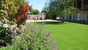 Un jardín cuidado con diversas flores y césped frente a un edificio con terraza.