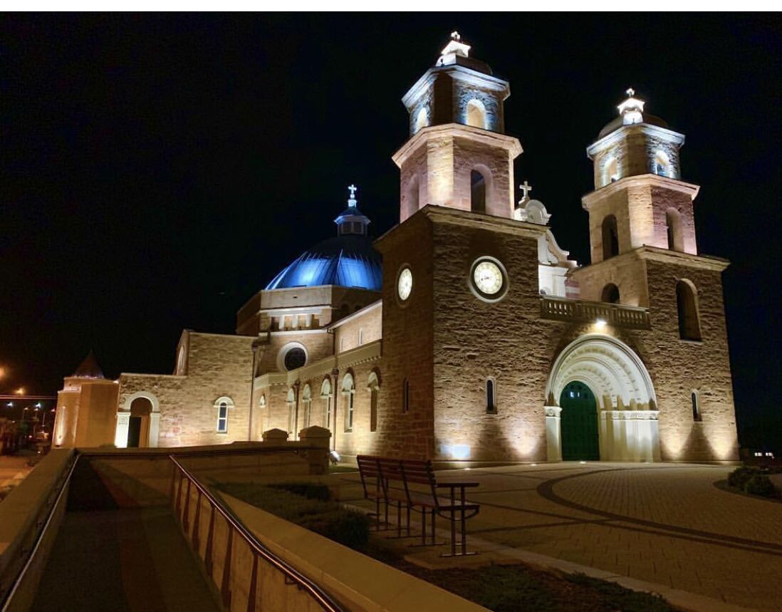 A historic building with a large dome and two bell towers, featuring a prominent entrance and a paved walkway.