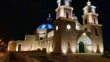 A historic building with a large dome and two bell towers, featuring a prominent entrance and a paved walkway.