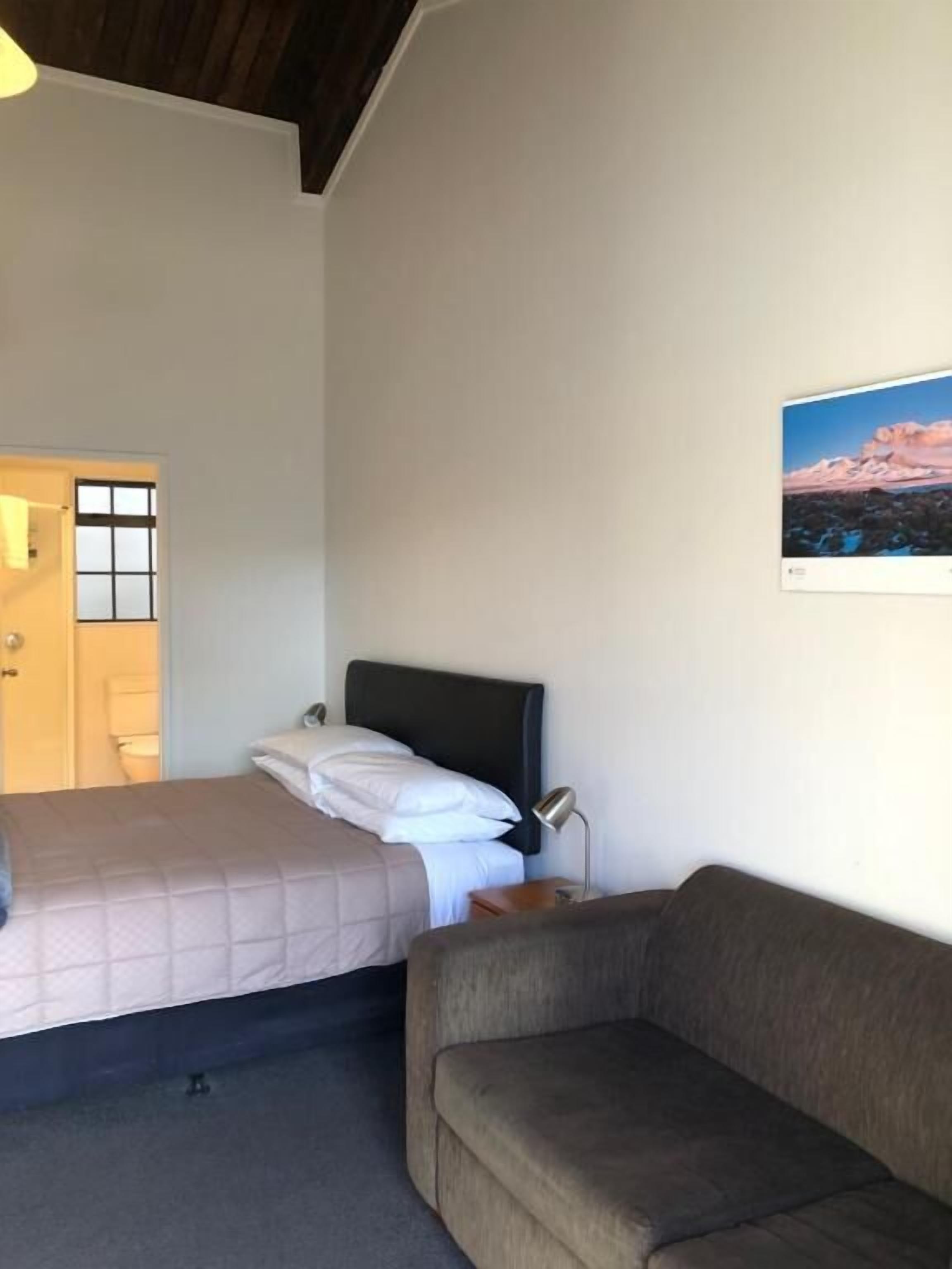 Ein Zimmer mit einem Bett, einem Schlafsofa, einem Nachttisch und einem Wandbild.