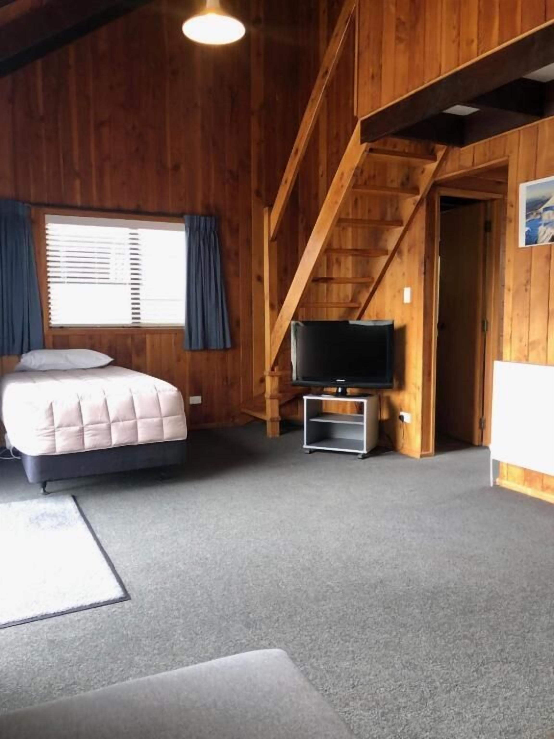 A room with a bed, a television, and a staircase.