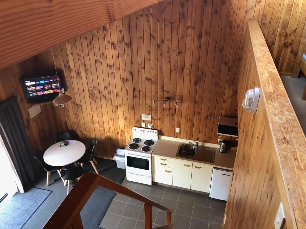 A compact kitchen with a stove, sink, and white cabinets.