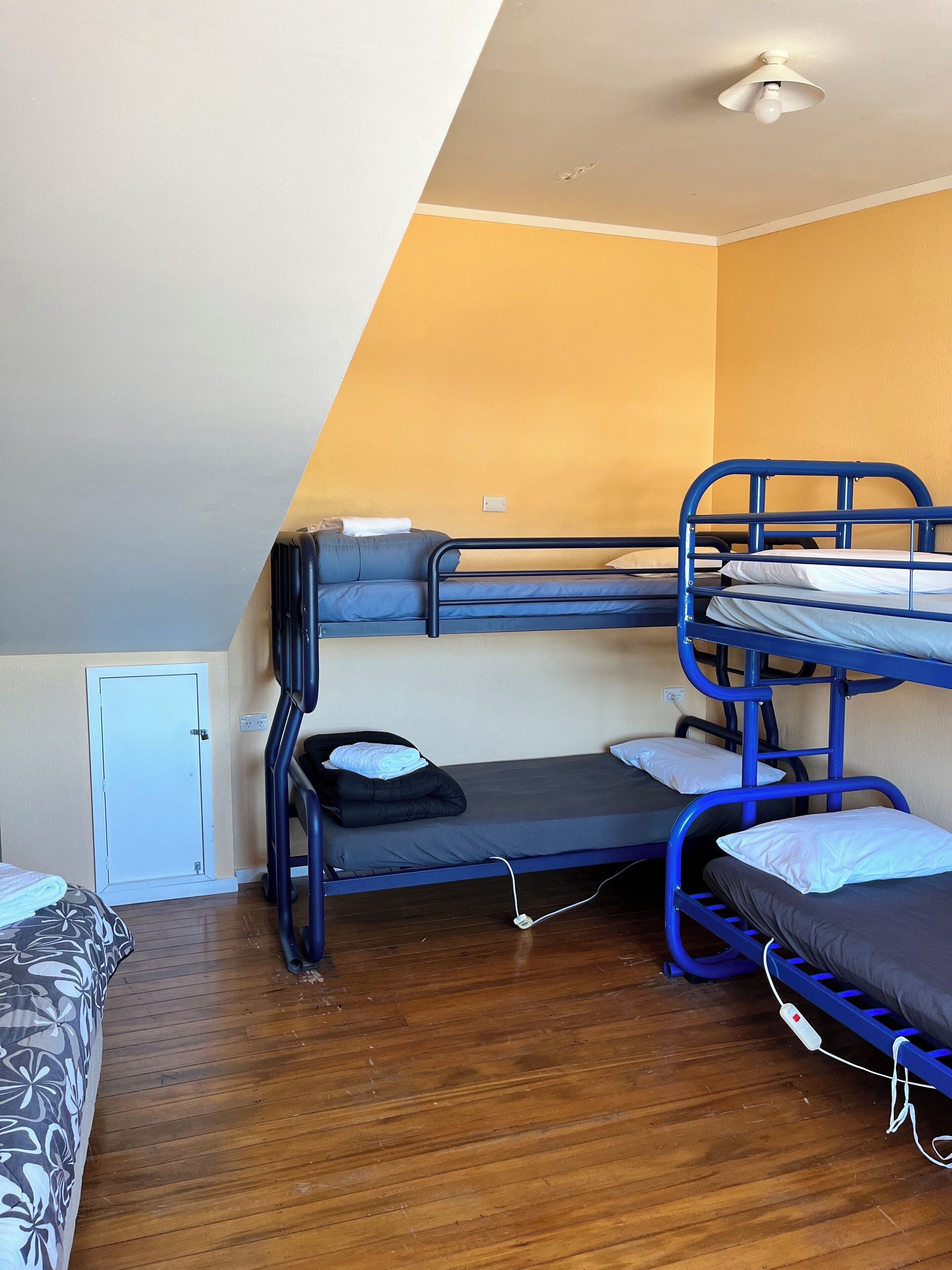 Ein Schlafraum mit Etagenbetten, einem Deckenventilator, einem kleinen Schrank und einem gemusterten Schlafsofa.
