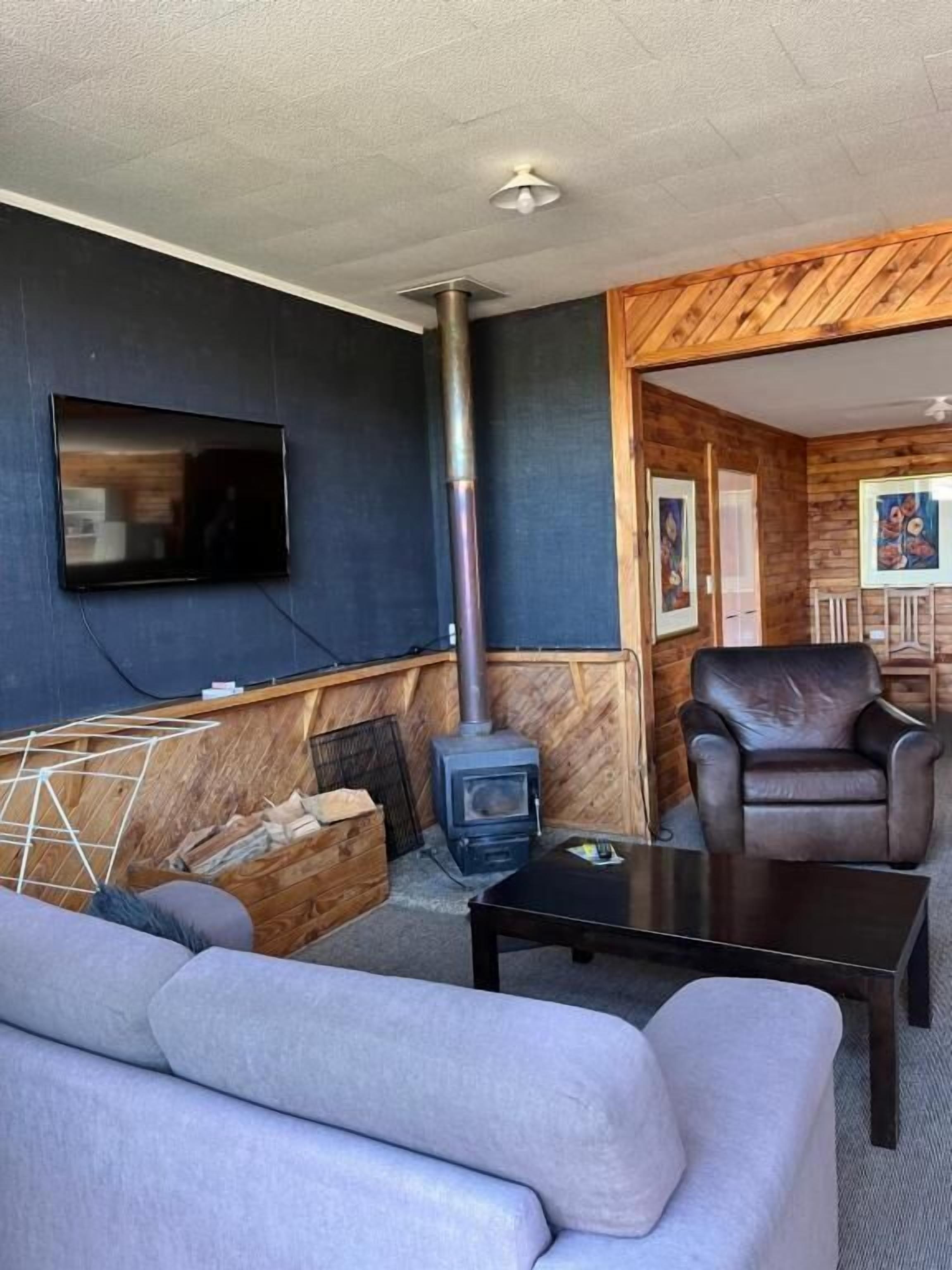 A cozy living area with a sofa, a coffee table, a fireplace, and a television mounted on the wall.