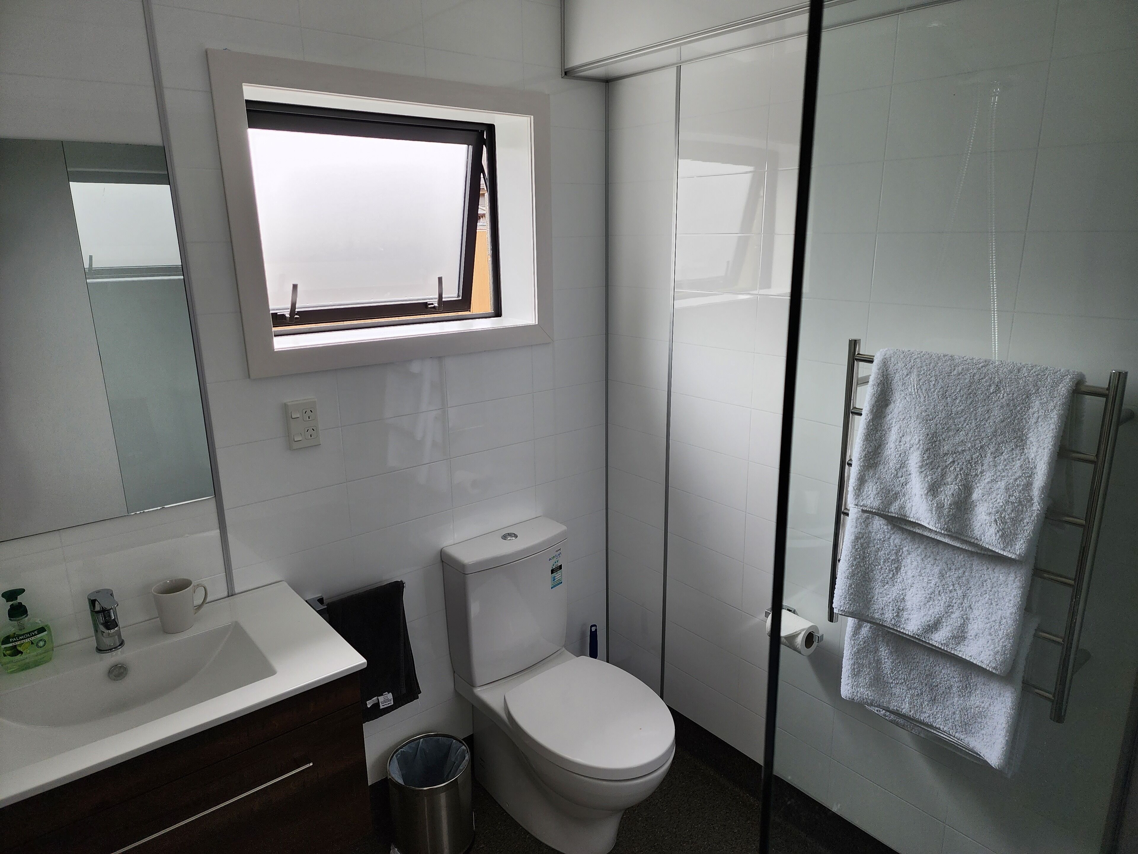 A modern bathroom with a toilet, sink, and a glass shower enclosure.