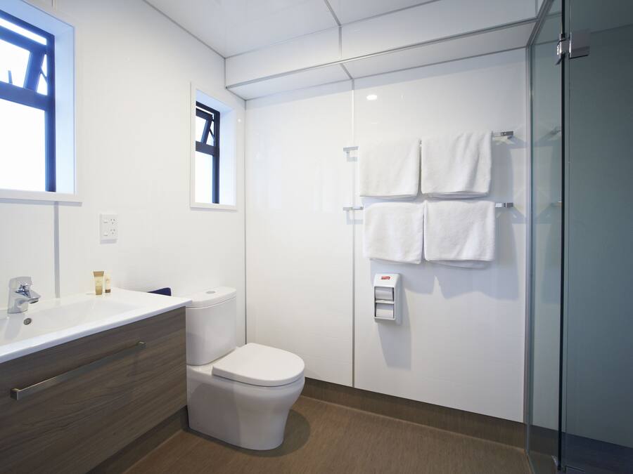 A modern bathroom with a white sink, toilet, and glass shower enclosure.