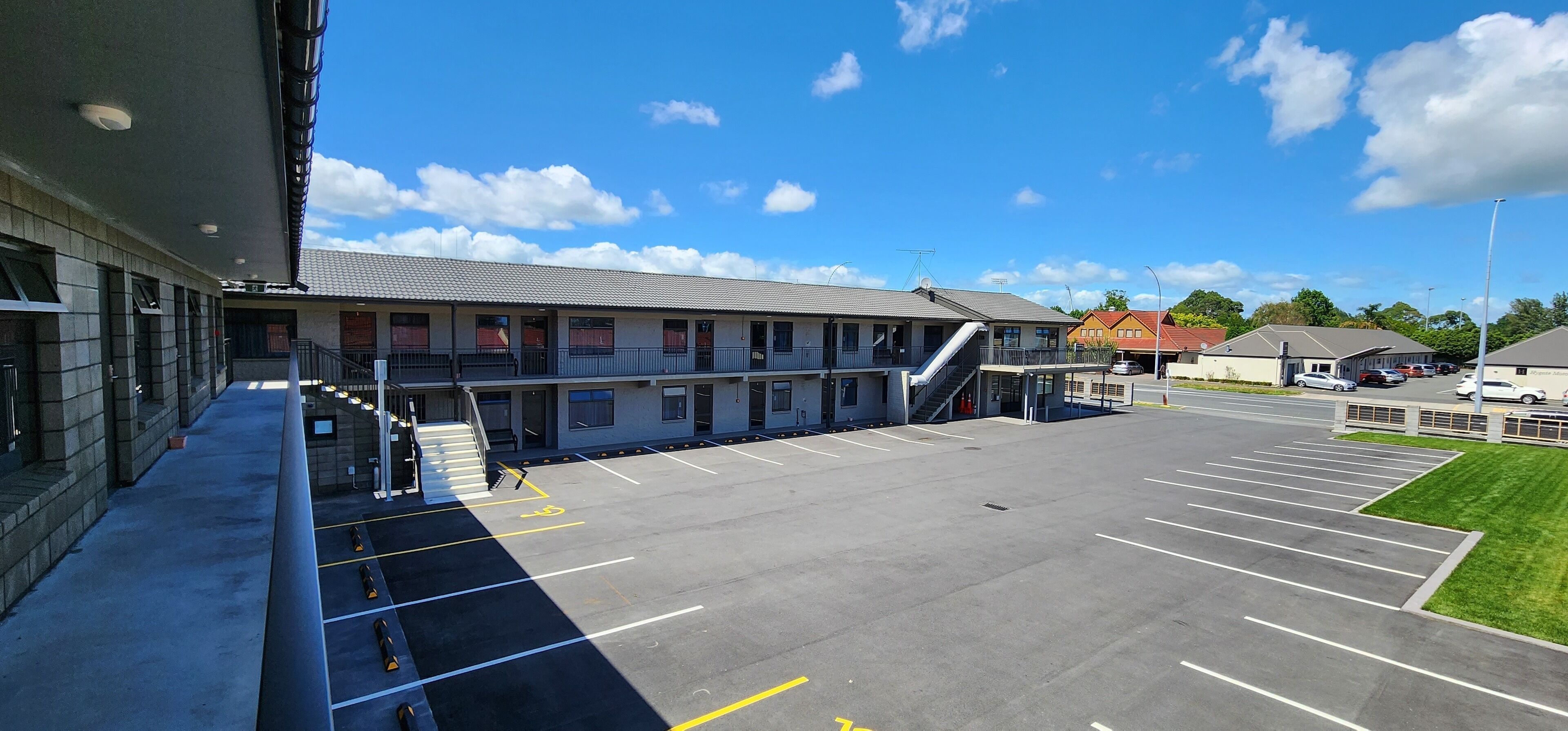 A building with a parking lot, a staircase, and a flat roof.