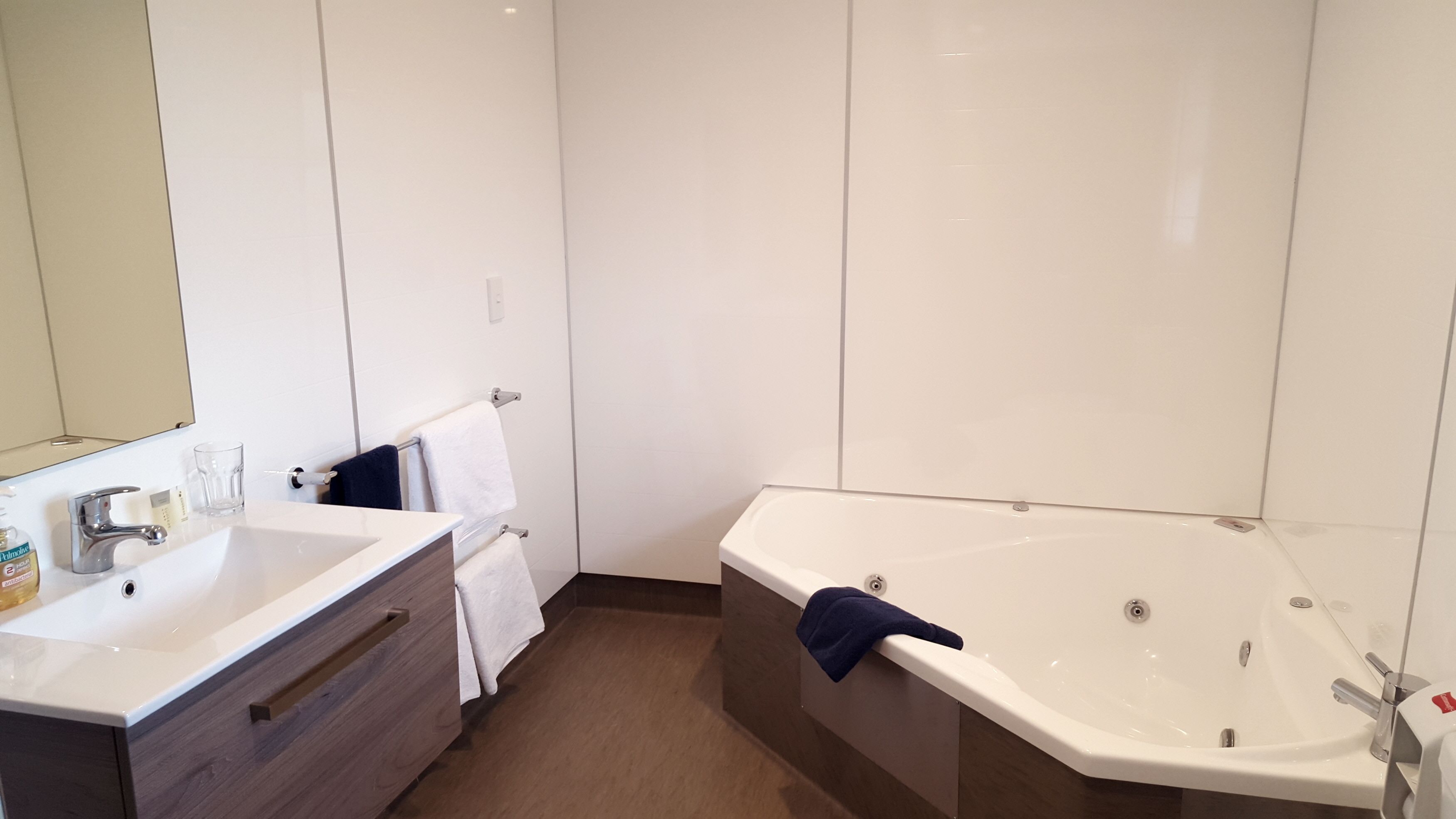 Une salle de bain moderne avec une grande baignoire, un meuble-lavabo avec un miroir et un évier.