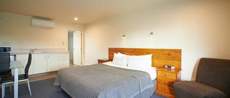 A bedroom with a bed, bedside table, chair, and a small desk with a chair.
