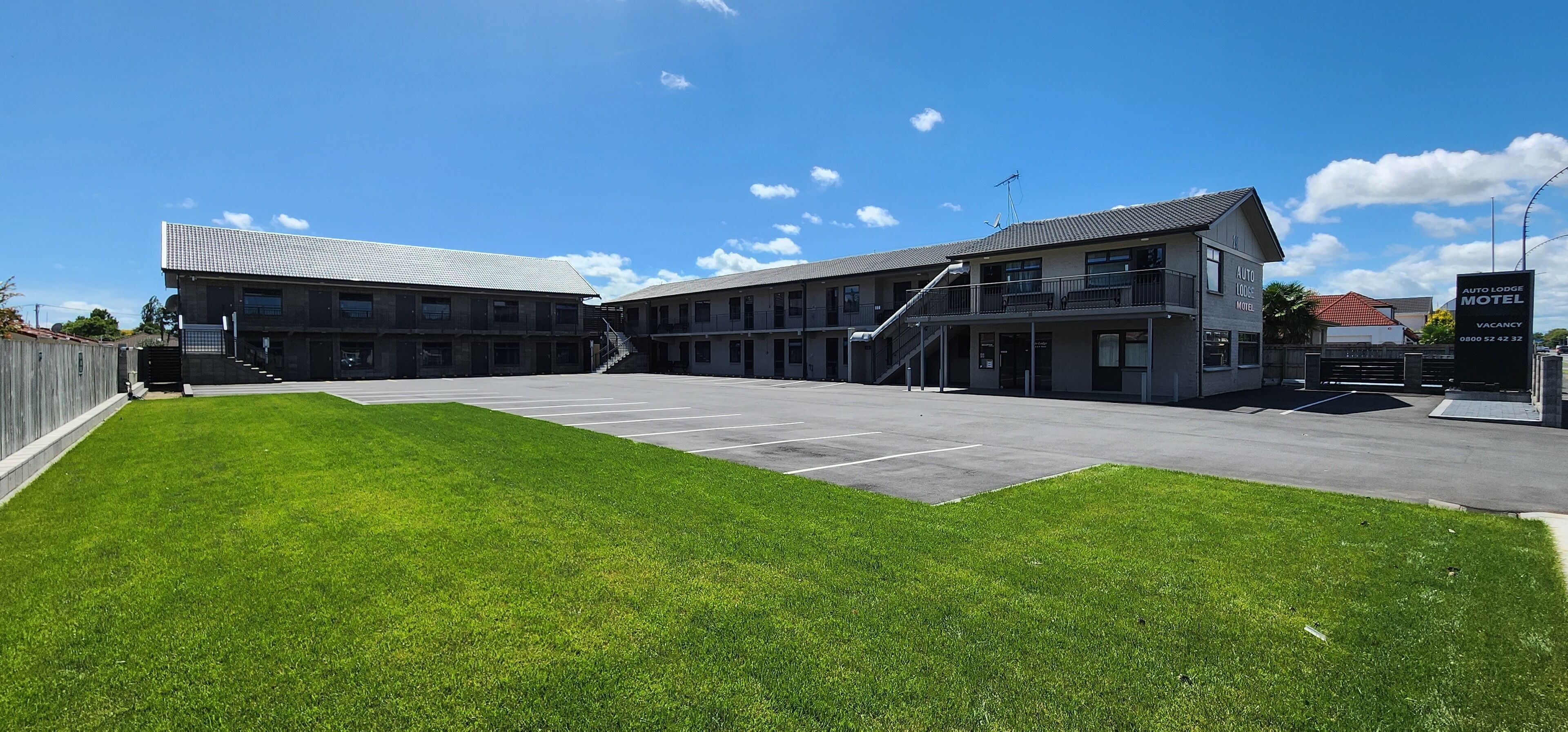 A motel with a parking lot and a grassy area in front.