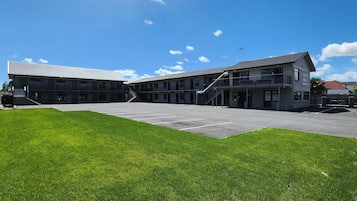 A motel with a parking lot and a grassy area in front.