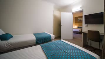 Una habitación de hotel con dos camas, un escritorio, una silla y un televisor en la pared.