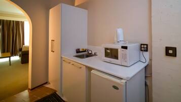 A compact kitchenette with a microwave, a small sink, and a refrigerator.