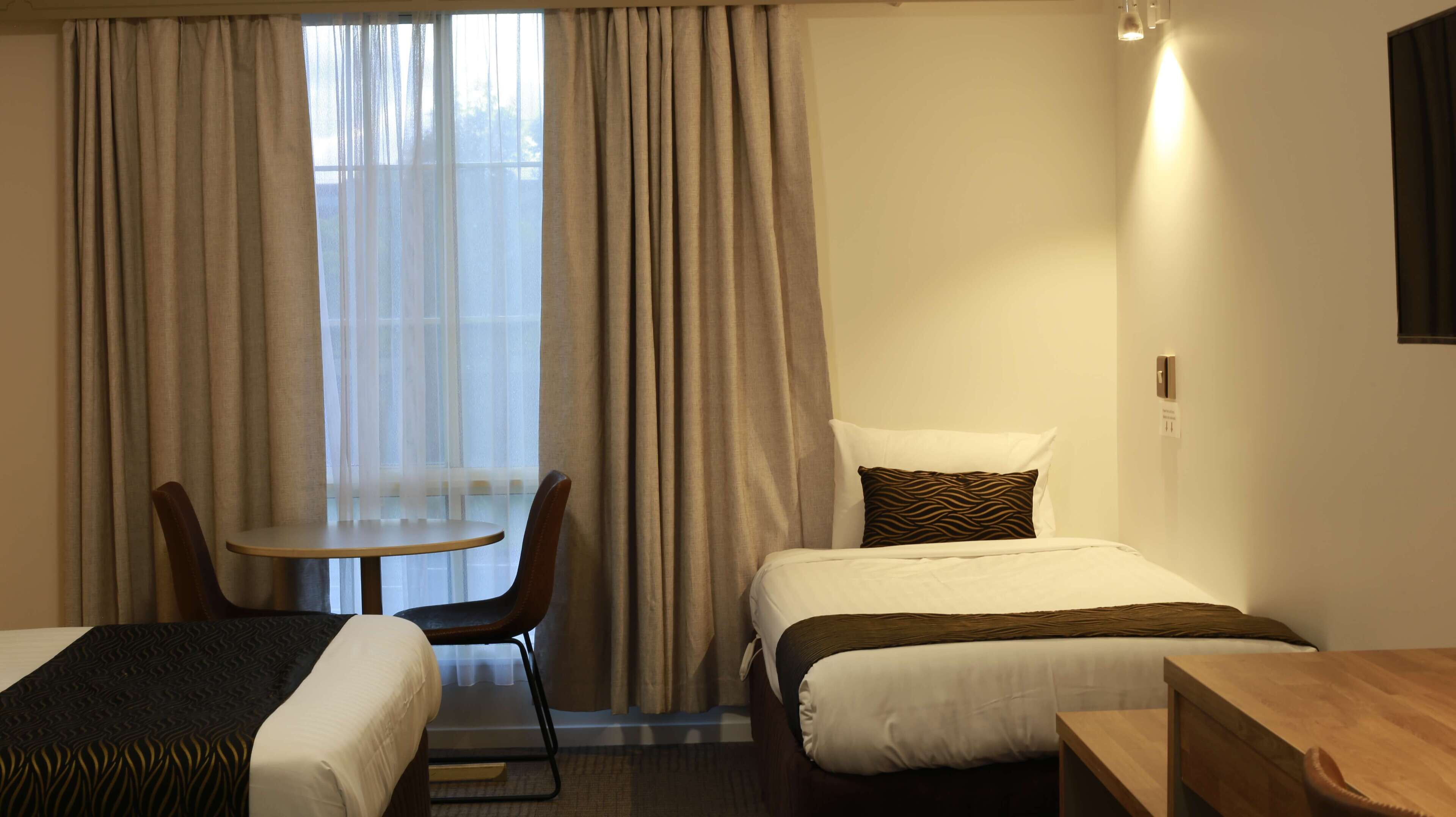 Une chambre d’hôtel avec deux lits, une petite table et une chaise.