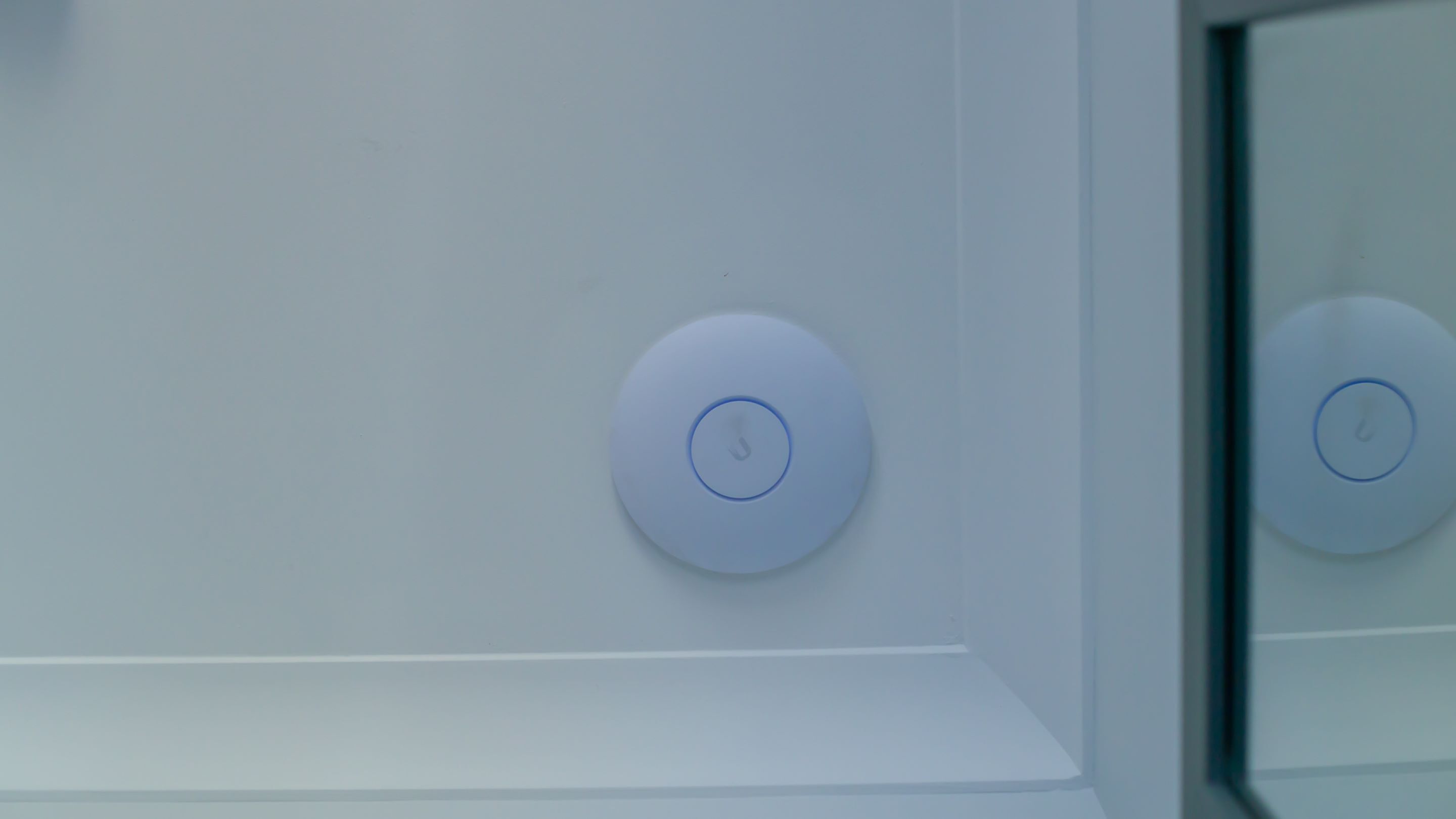 Un appareil fixé au mur, doté d’une interface circulaire, qui pourrait être un panneau de commande ou un capteur.
