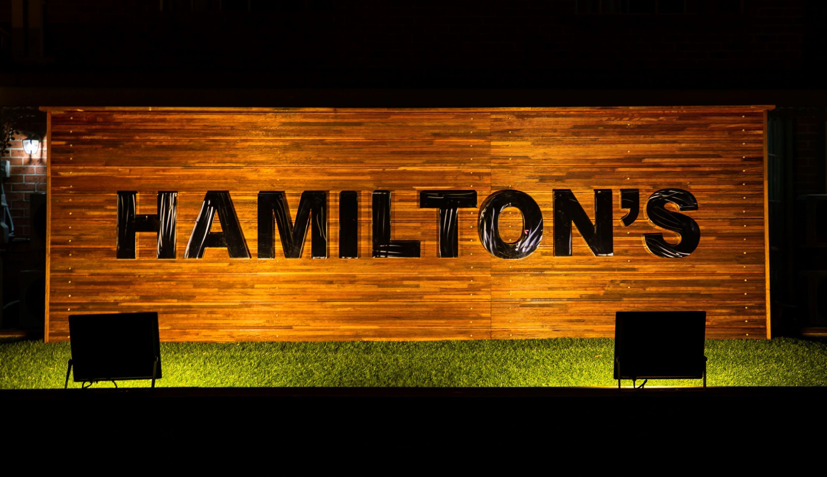 Un muro di legno con la scritta "HAMILTON'S" in grandi lettere nere.