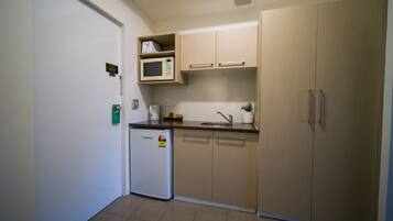 A compact kitchen with a refrigerator, microwave, sink, and wooden cabinets.