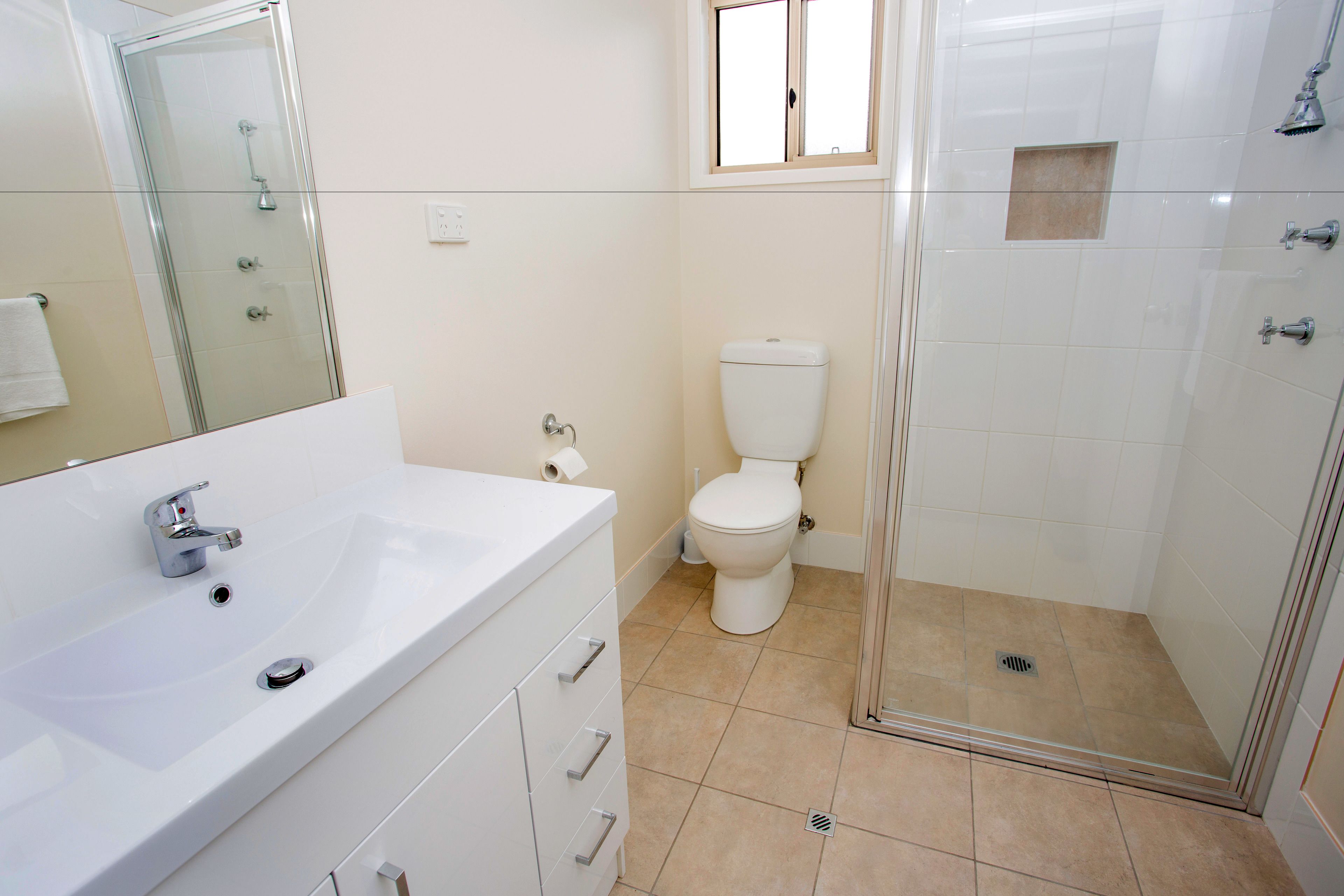 Une salle de bain avec une douche à parois de verre, un lavabo blanc et des toilettes.