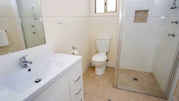 Une salle de bain avec une douche à parois de verre, un lavabo blanc et des toilettes.