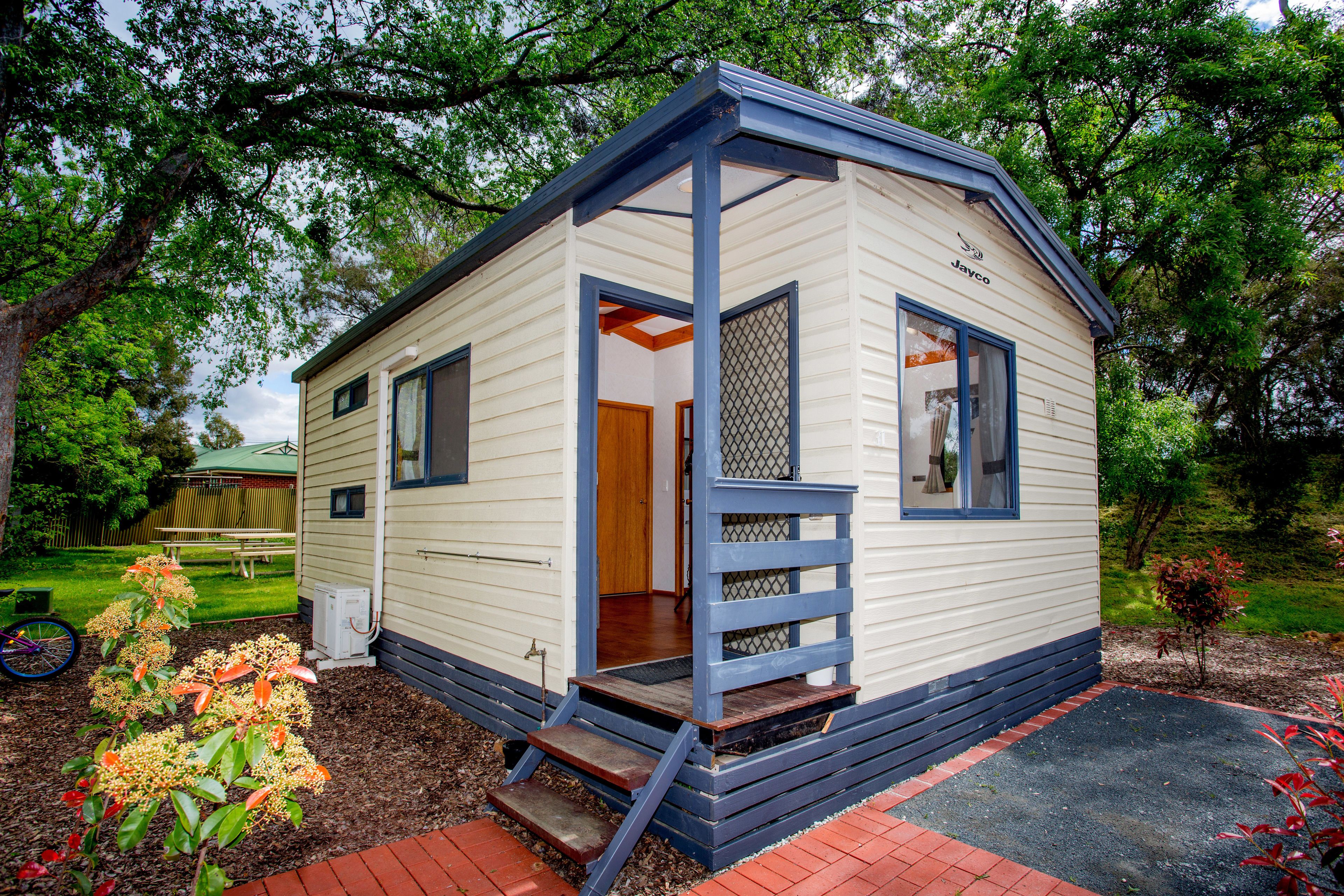 A small, single-story mobile home with a blue exterior and a wooden door.