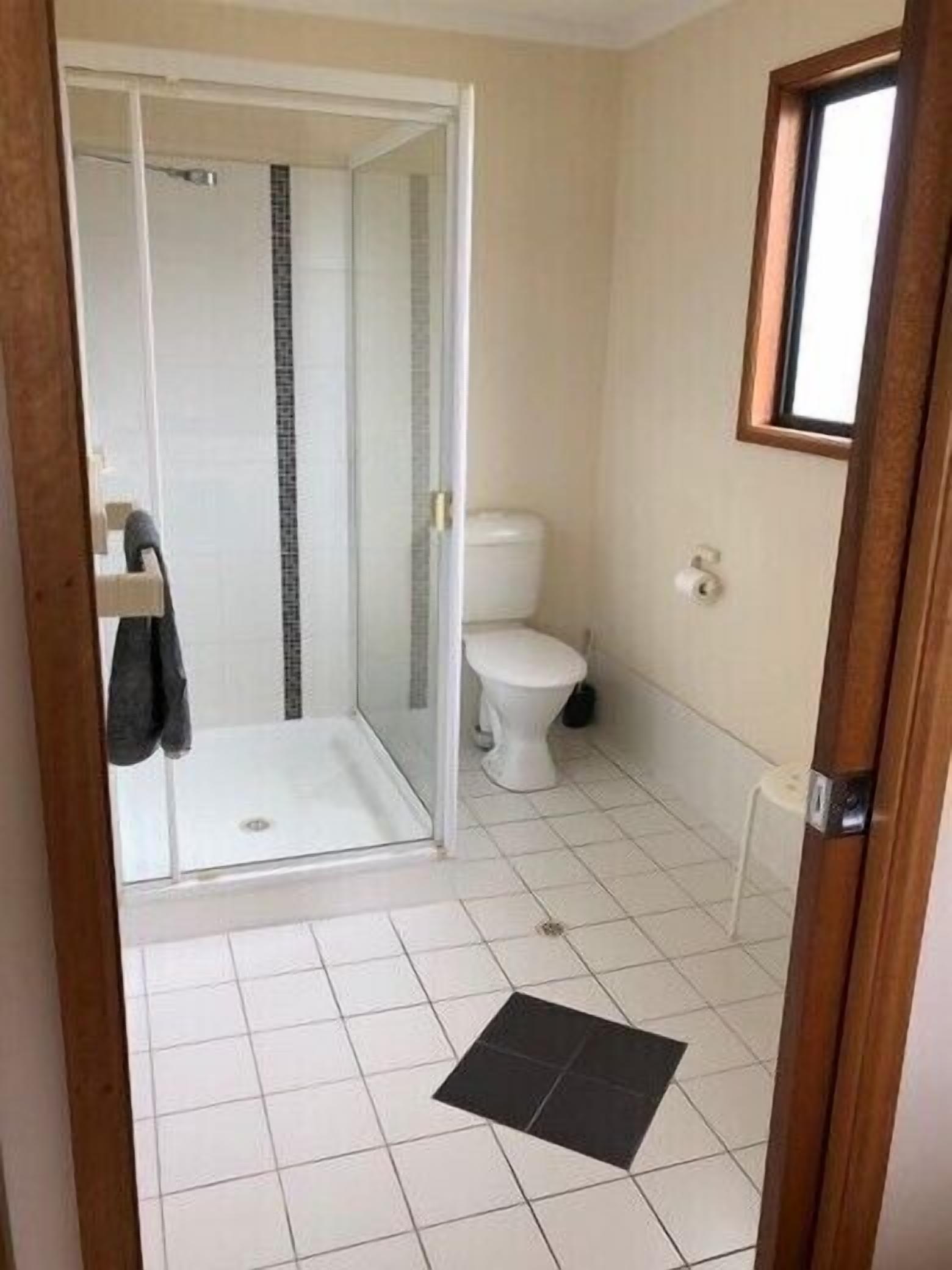 A bathroom with a glass shower enclosure, a toilet, and a small sink.