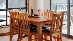 A dining area with a wooden table and chairs, large windows, and a view of the outdoors. - Waves and Wildlife (Stokes Bay)