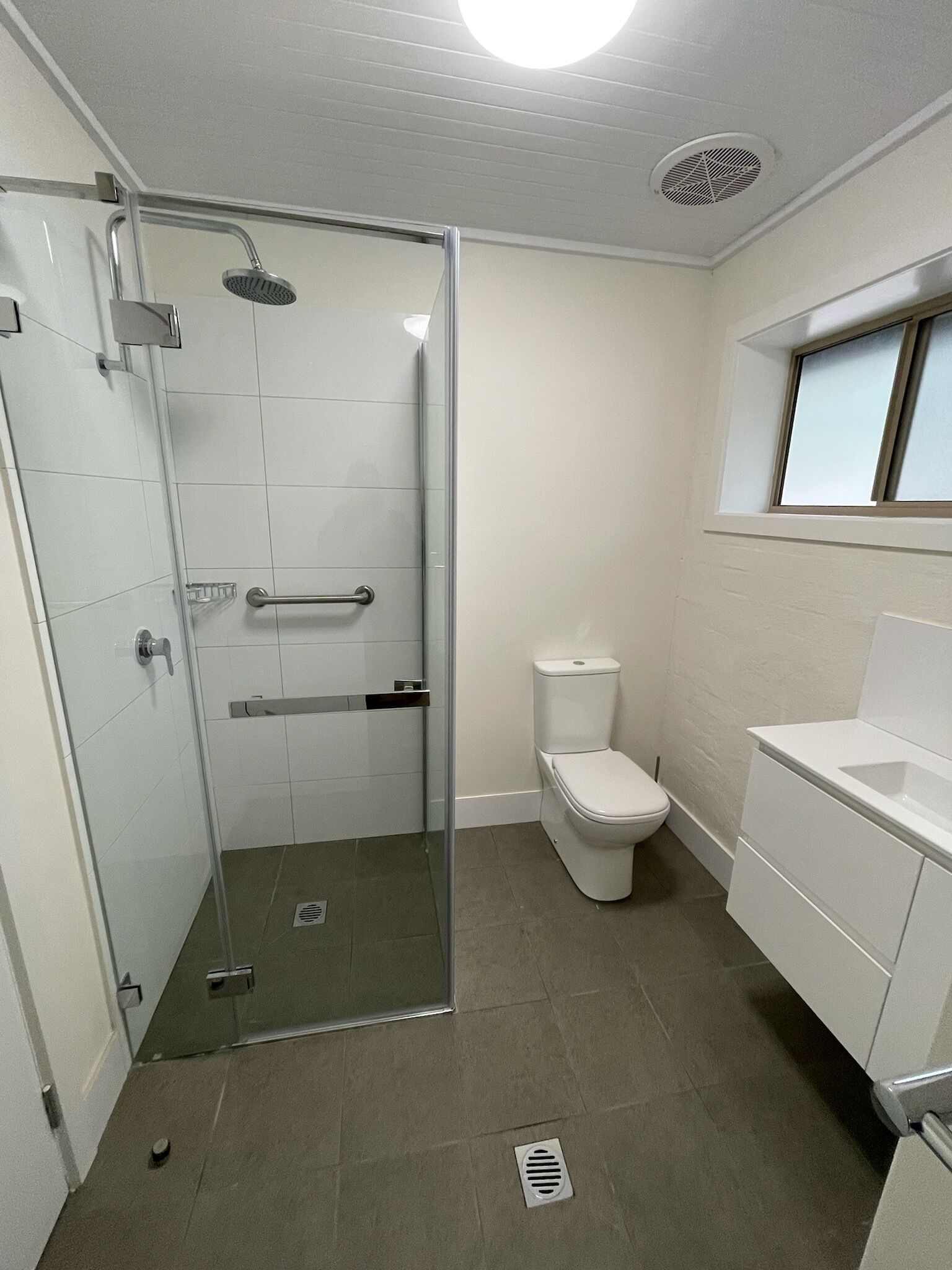 A modern bathroom with a glass shower enclosure, a toilet, and a sink.