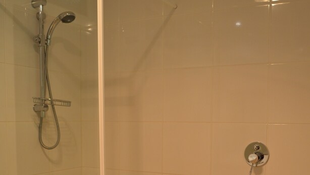 Un baño con ducha de vidrio, bañera y retrete.