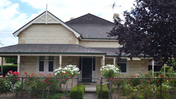 A two-story house with a porch, a front door, and a small front yard with flowers. - Tin House at Tanunda (Tanunda)