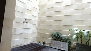 Un área de spa con pared de piedra, ducha y plantas en macetas.