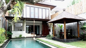 Una casa moderna con piscina, un porche cubierto y un jardín bien cuidado.