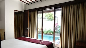 Habitación de hotel con cama, vista a una piscina y amplias puertas corredizas de vidrio.