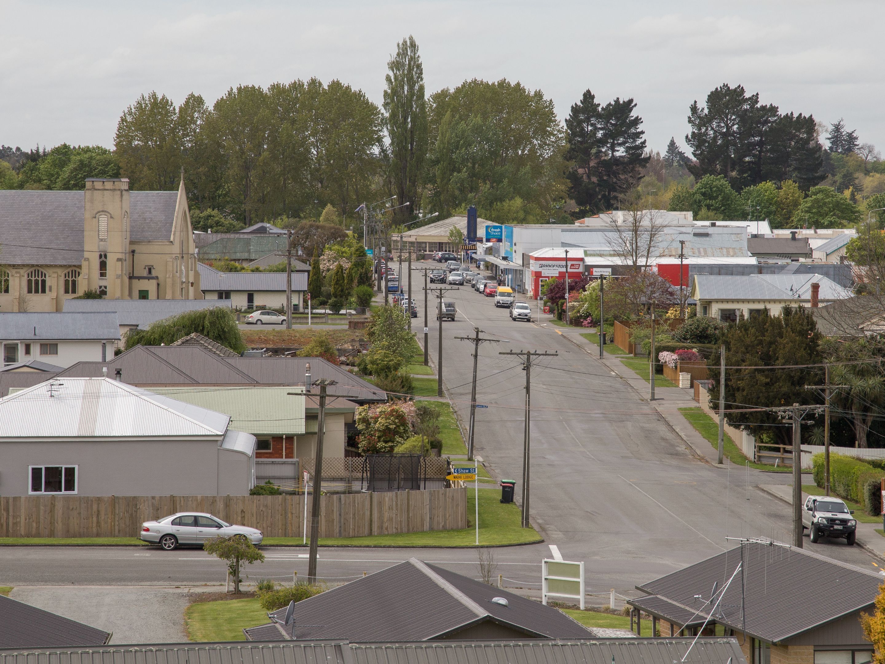 A street view with residential houses, a church, and a commercial area with shops.