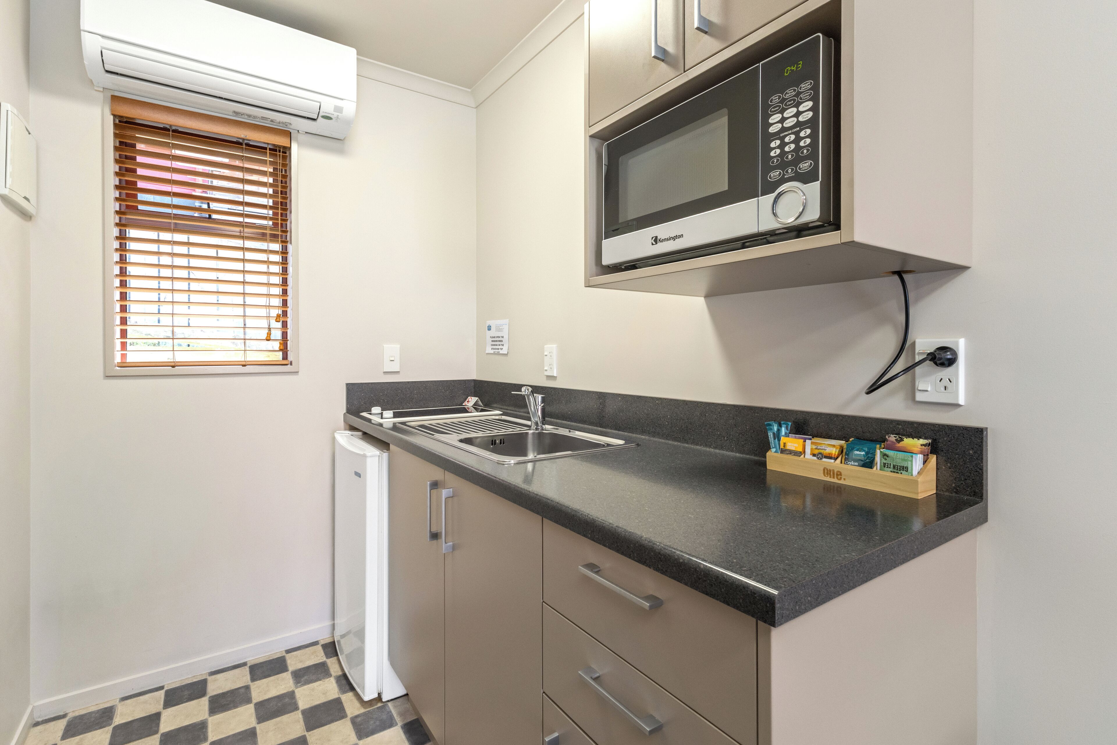 A compact kitchen with a built-in microwave, a sink, and a compact refrigerator.
